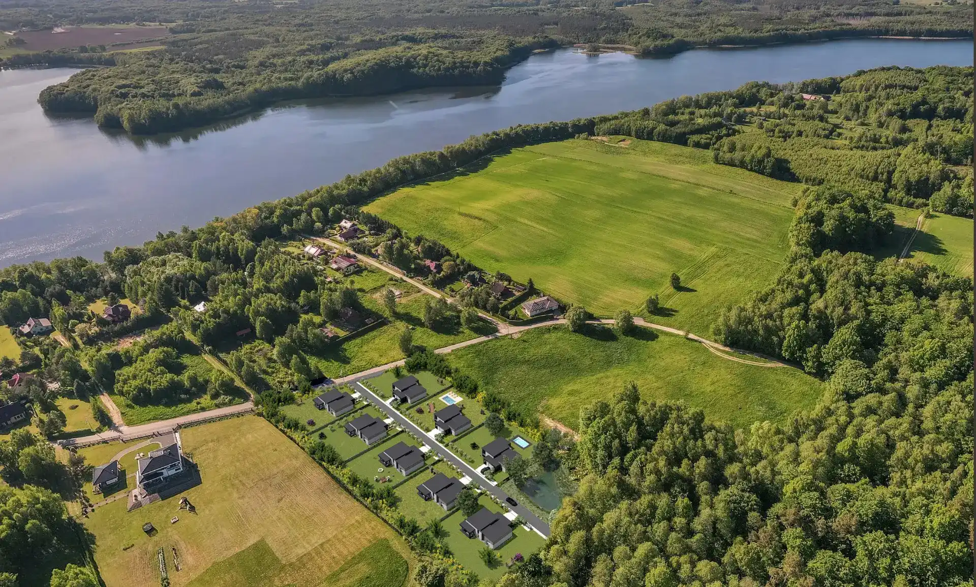Aerial render of a housing development by a forest and lake
